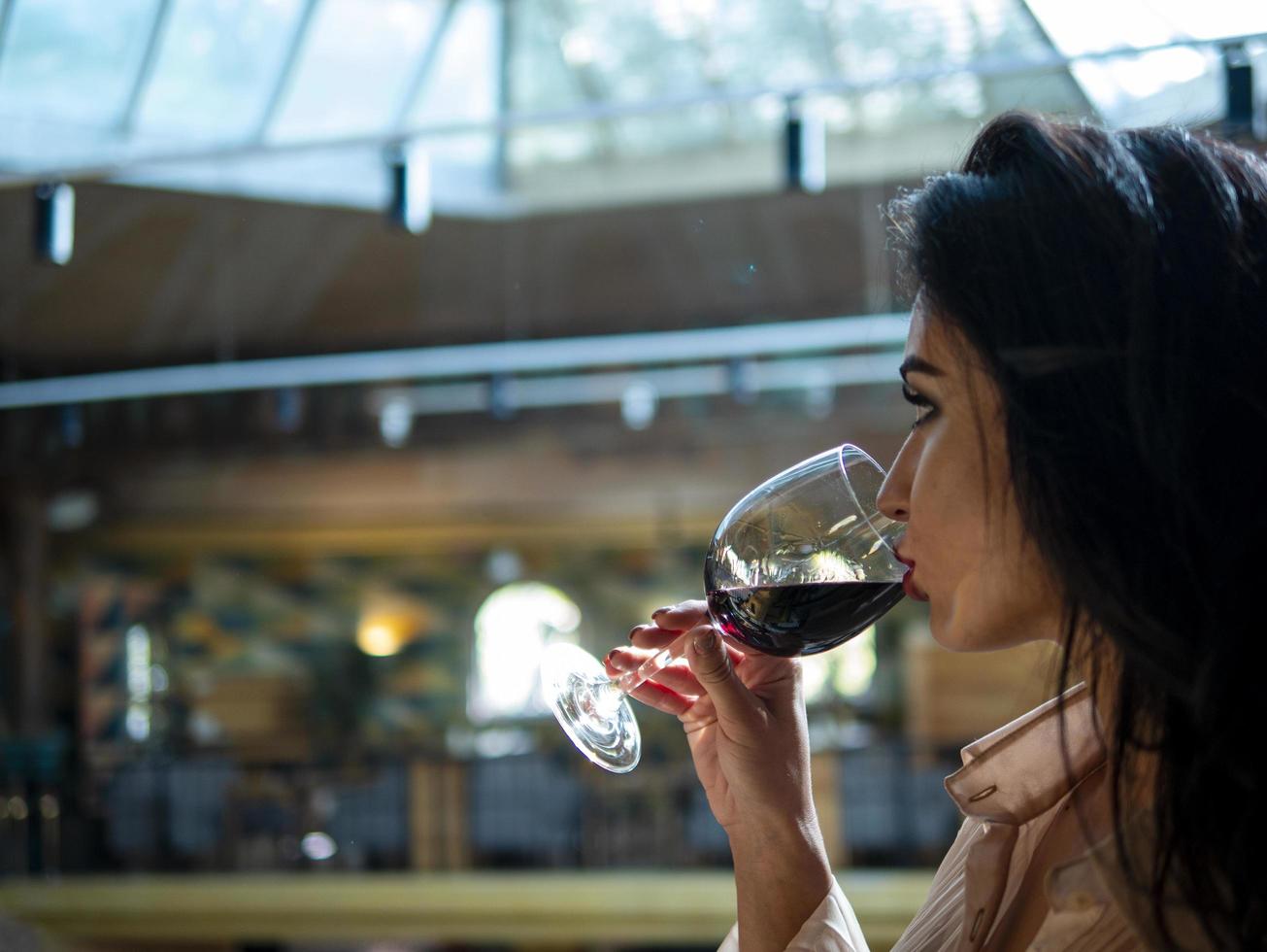 Portrait de modèle de fille brune buvant du vin rouge dans un verre photo