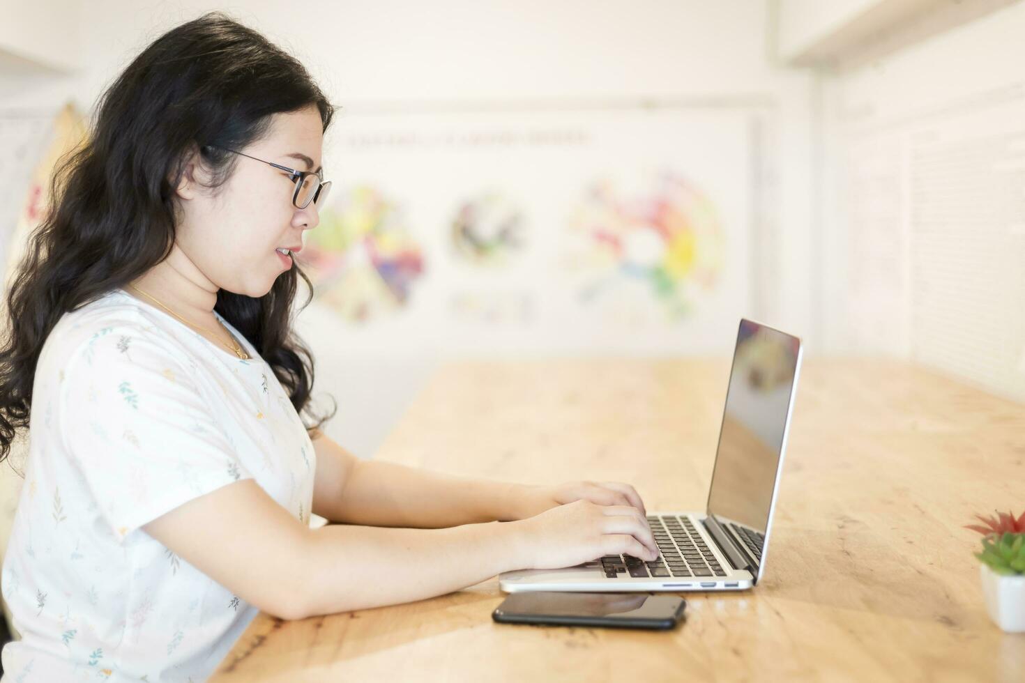 affaires asiatique femme travail avec téléphone intelligent et portable ordinateur sur dans café magasin comme le Contexte. photo