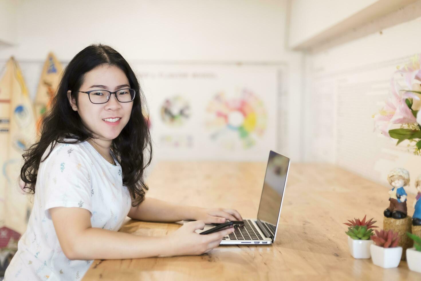 affaires asiatique femme travail avec téléphone intelligent et portable ordinateur sur dans café magasin comme le Contexte. photo