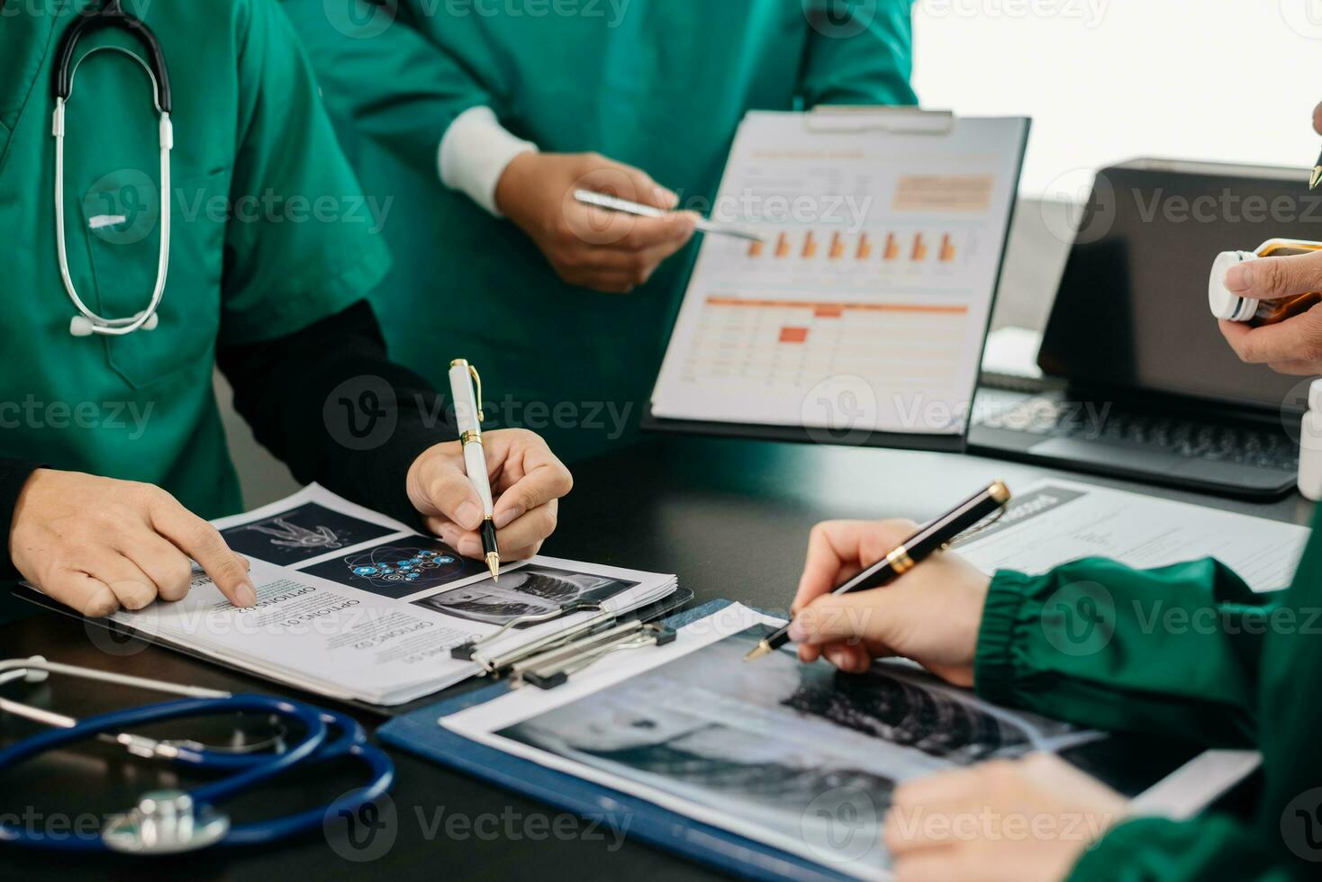 médical équipe ayant une réunion avec médecins dans blanc laboratoire manteaux et chirurgical gommages assise à une table discuter une les patients travail en ligne en utilisant des ordinateurs dans le médical photo