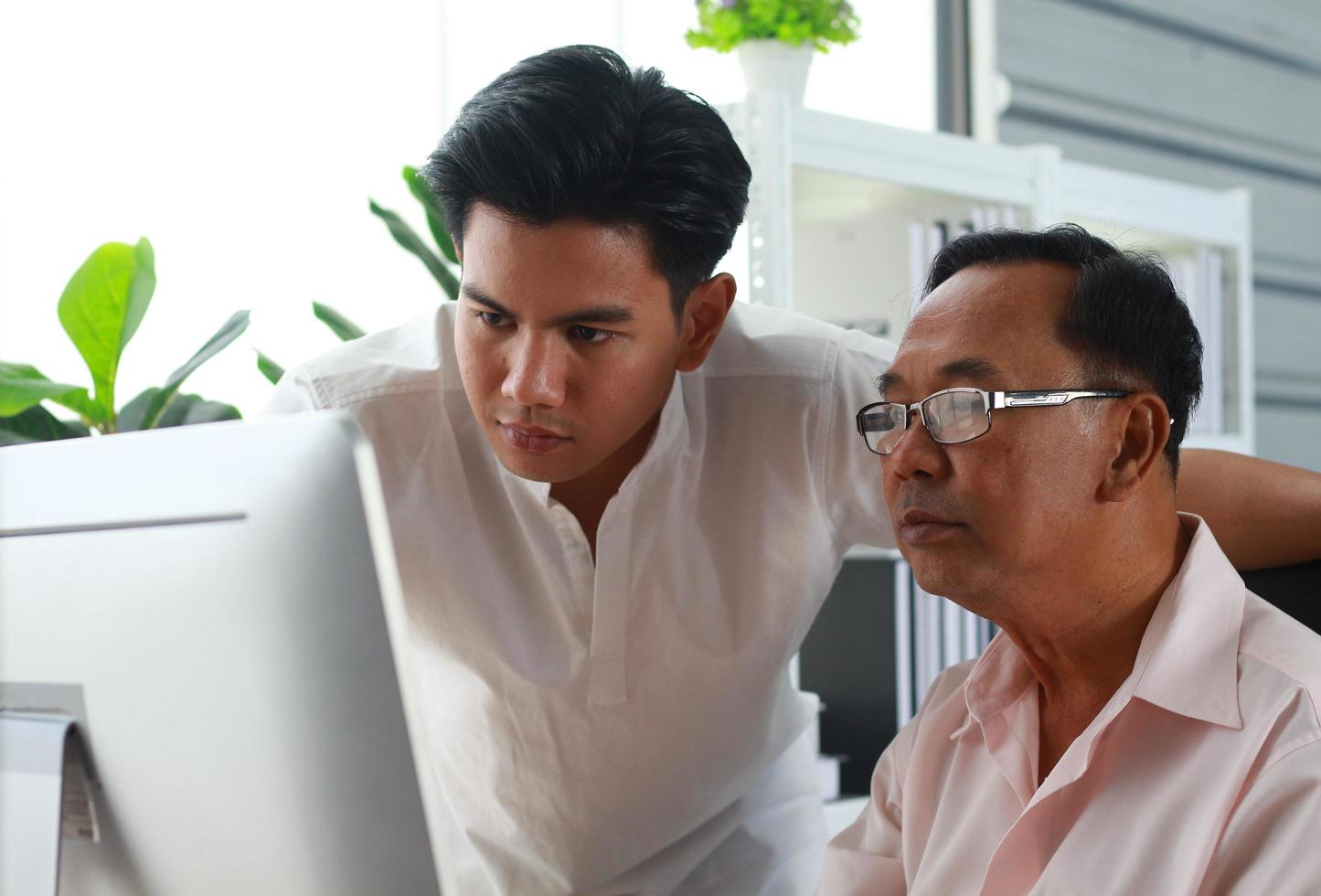 le fils apprend à son père à utiliser l'ordinateur photo