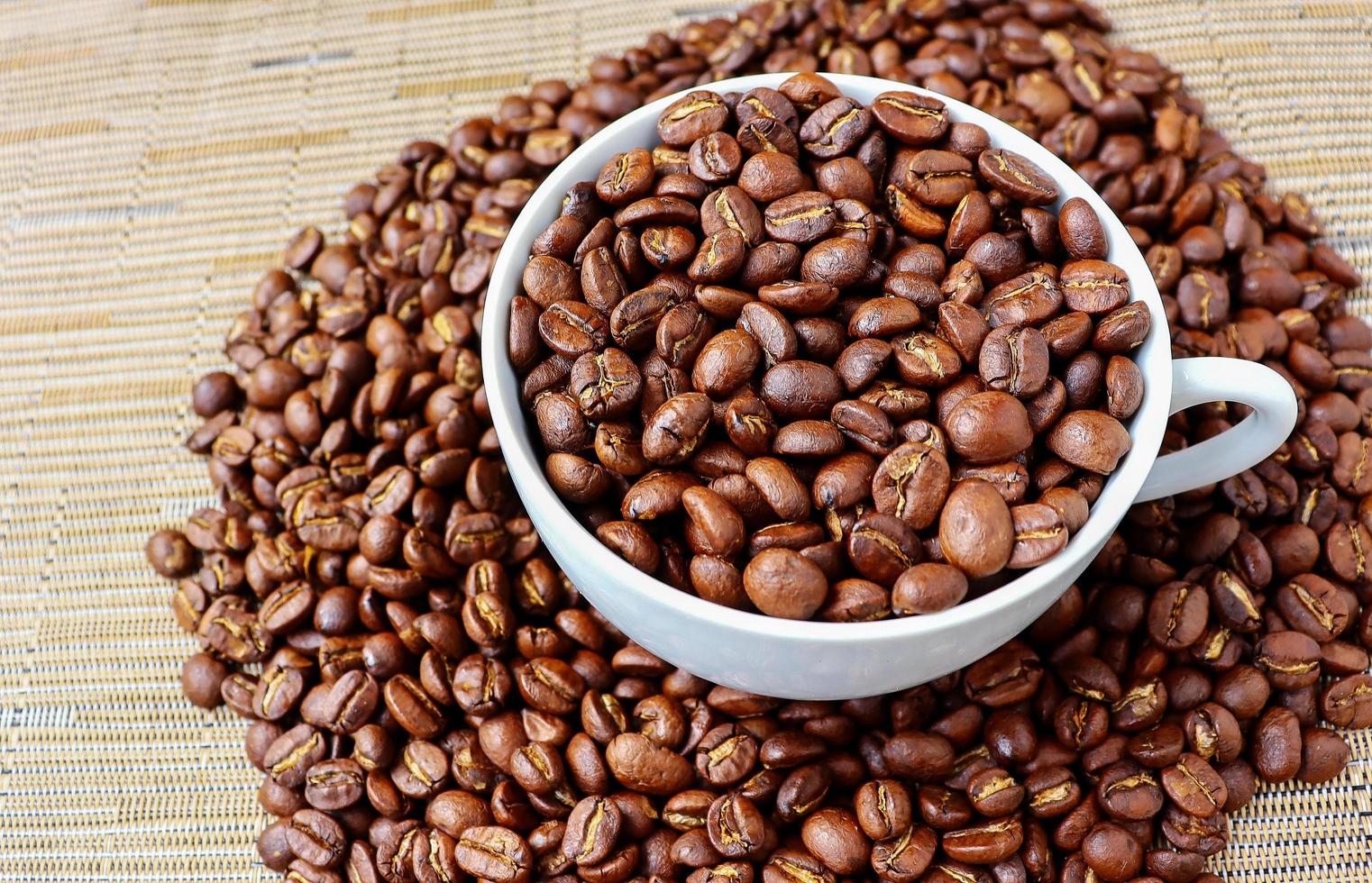 grains de café dans une tasse blanche sur plancher en bois photo