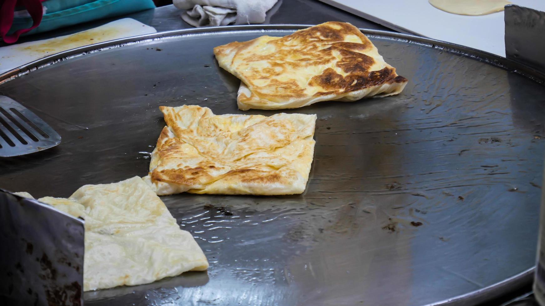 fabrication de roti, roti frit sur poêle à frire, nourriture de rue traditionnelle indienne photo