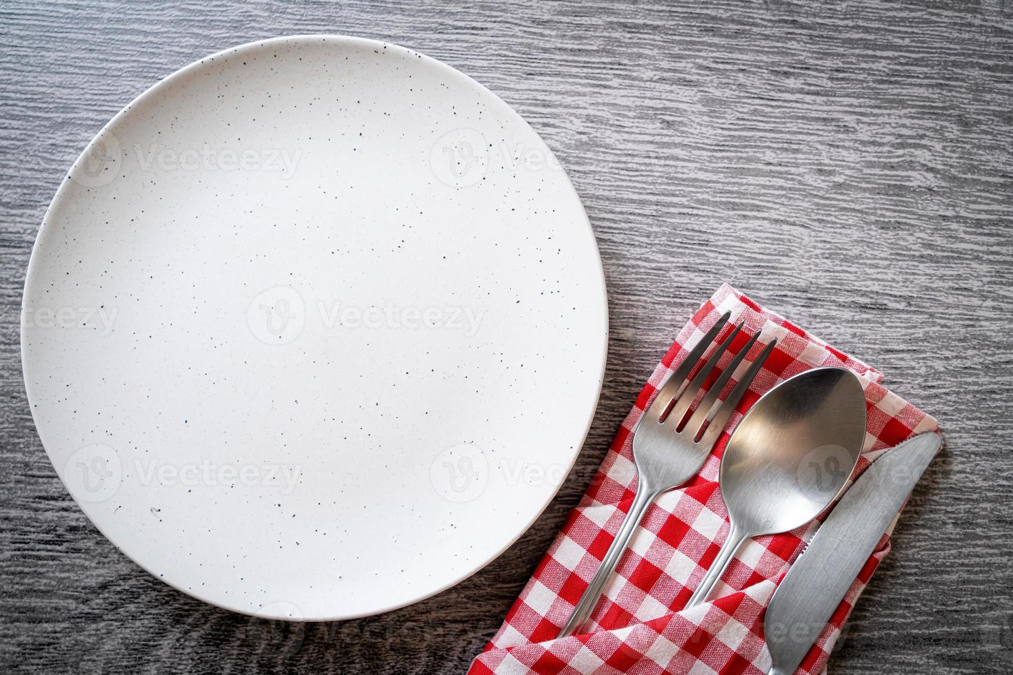 assiette ou plat vide avec couteau, fourchette et cuillère sur fond de carreaux de bois photo