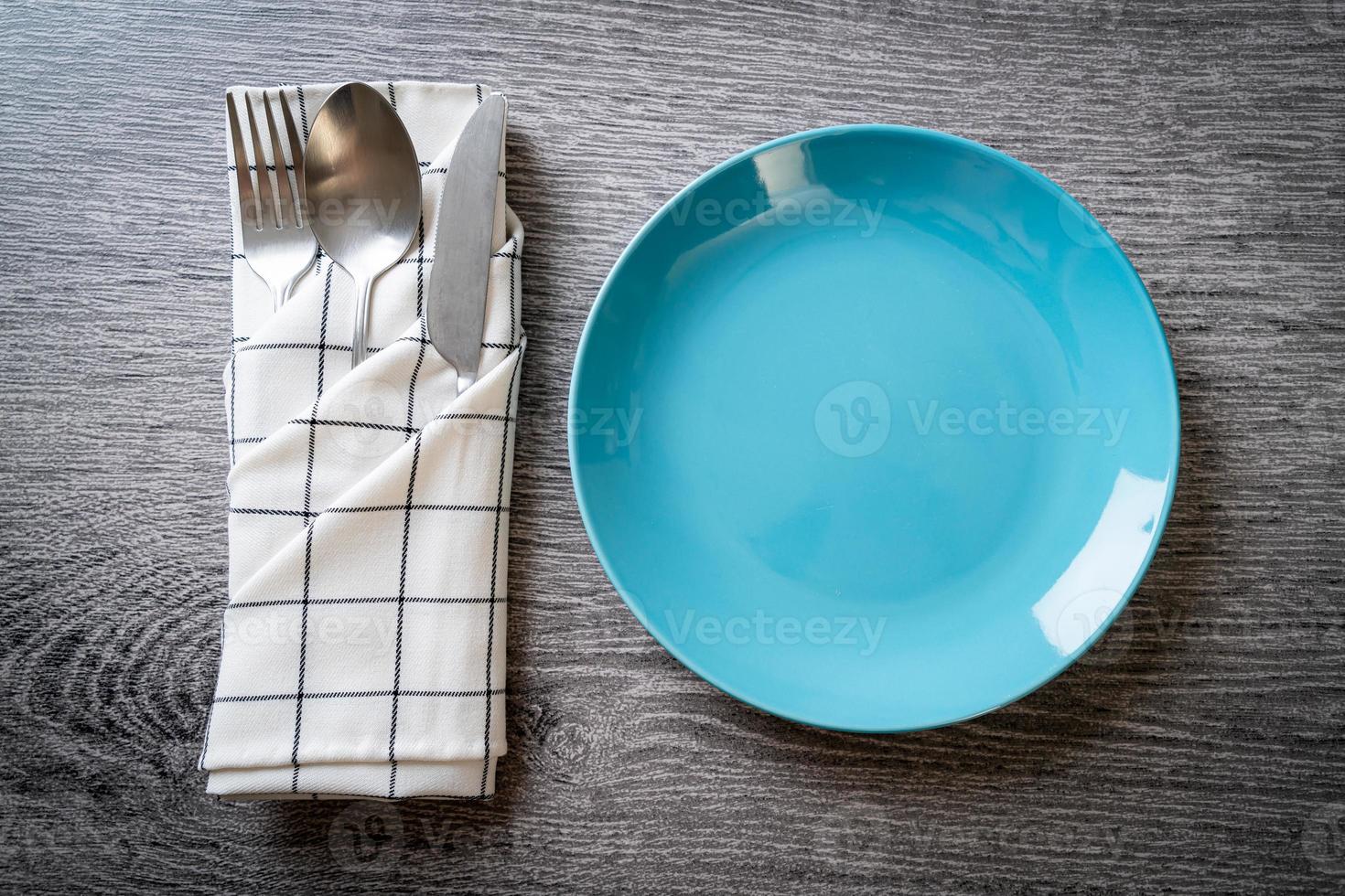 assiette ou plat vide avec couteau, fourchette et cuillère sur fond de carreaux de bois photo