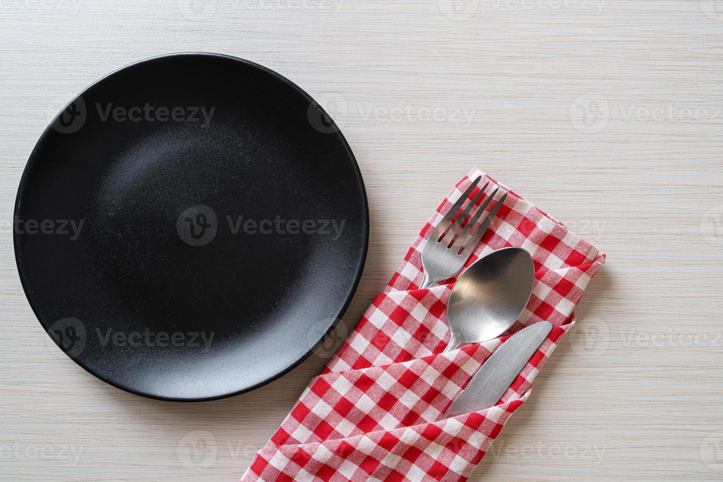 assiette ou plat vide avec couteau, fourchette et cuillère sur fond de carreaux de bois photo