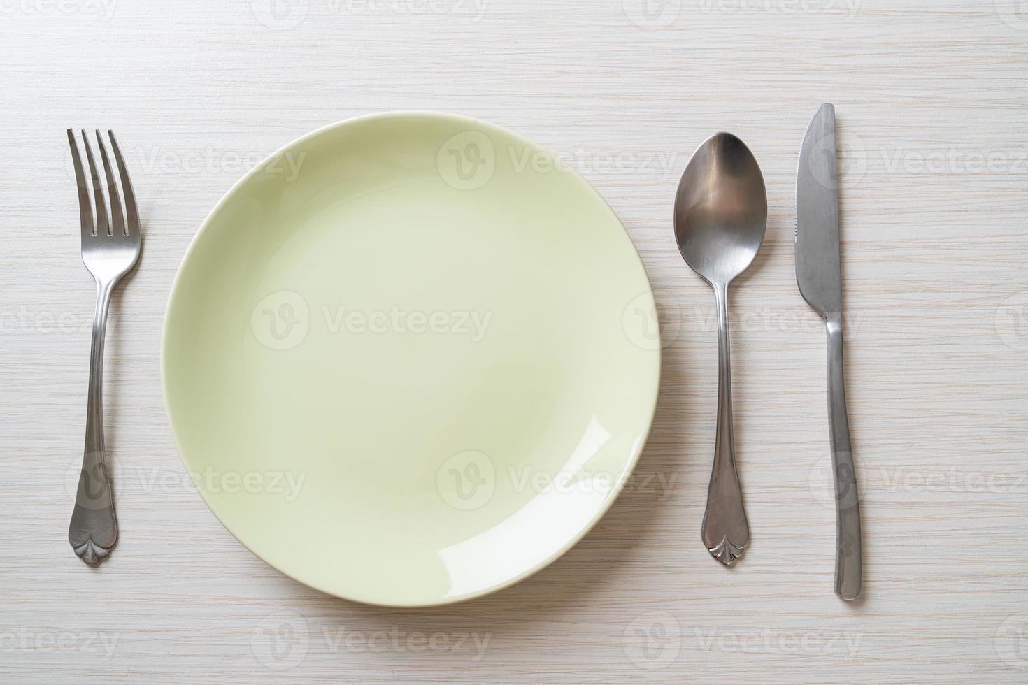 assiette ou plat vide avec couteau, fourchette et cuillère sur fond de carreaux de bois photo