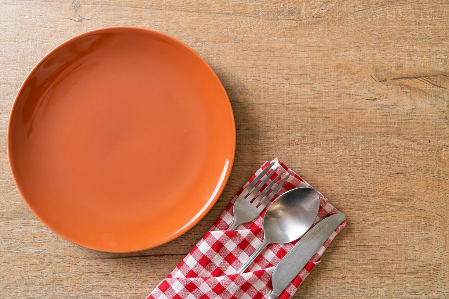 assiette ou plat vide avec couteau, fourchette et cuillère sur fond de carreaux de bois photo