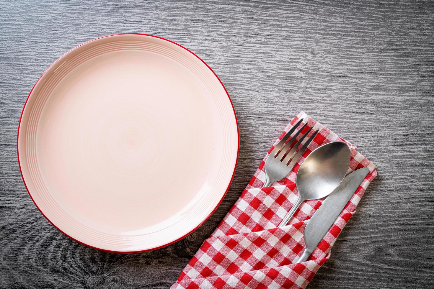 assiette ou plat vide avec couteau, fourchette et cuillère sur fond de carreaux de bois photo