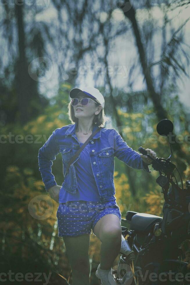 jolie femme permanent à côté de petit enduro moto contre Naturel Contexte photo