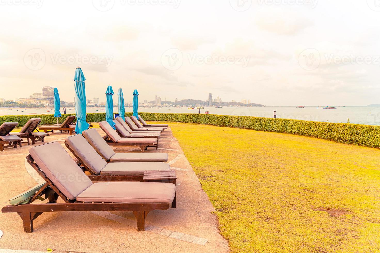 chaise piscine ou lit piscine et parasol autour de la piscine avec fond de plage de mer à pattaya en thaïlande photo