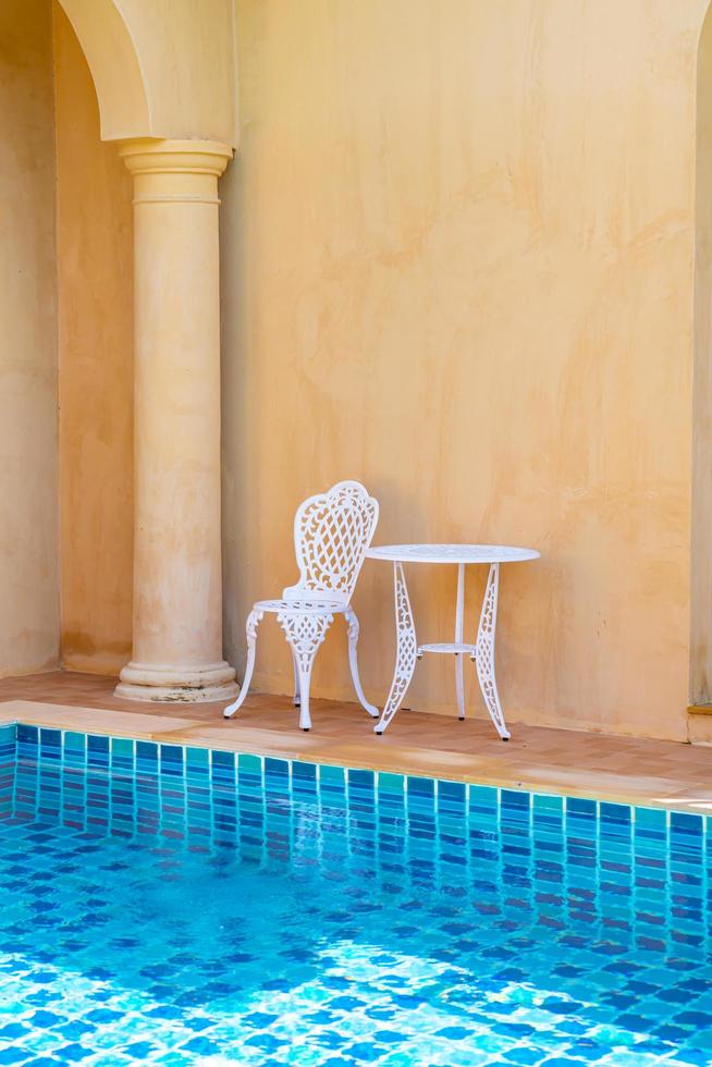 chaise et table blanches vides du côté de la piscine photo