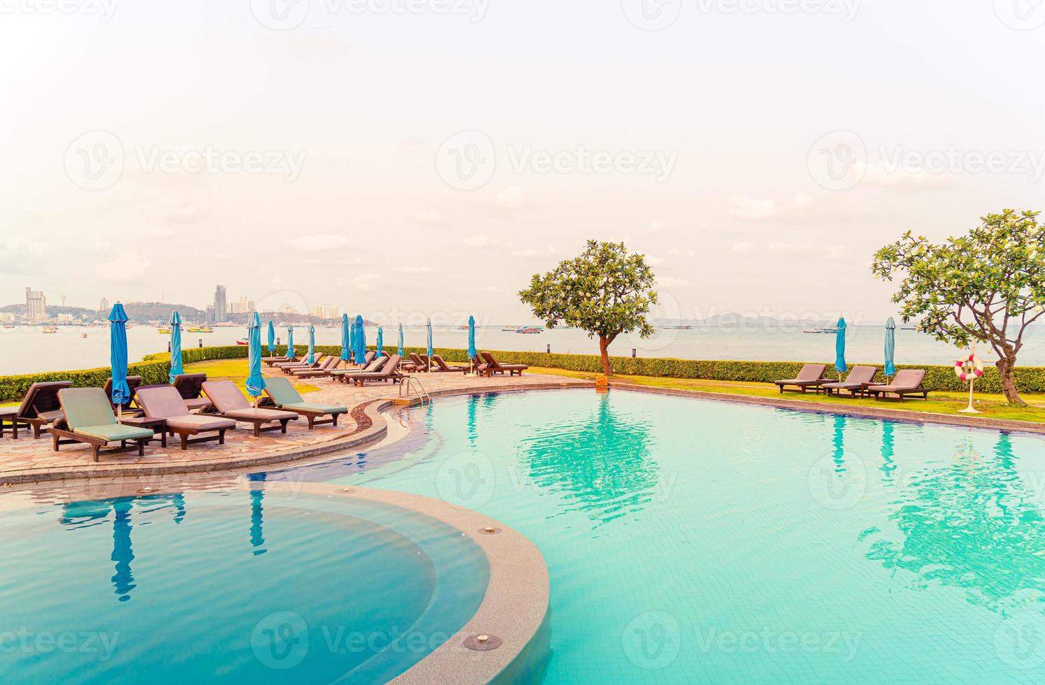 piscines de chaise ou piscines de lit et parasols autour de la piscine avec fond de plage de mer photo