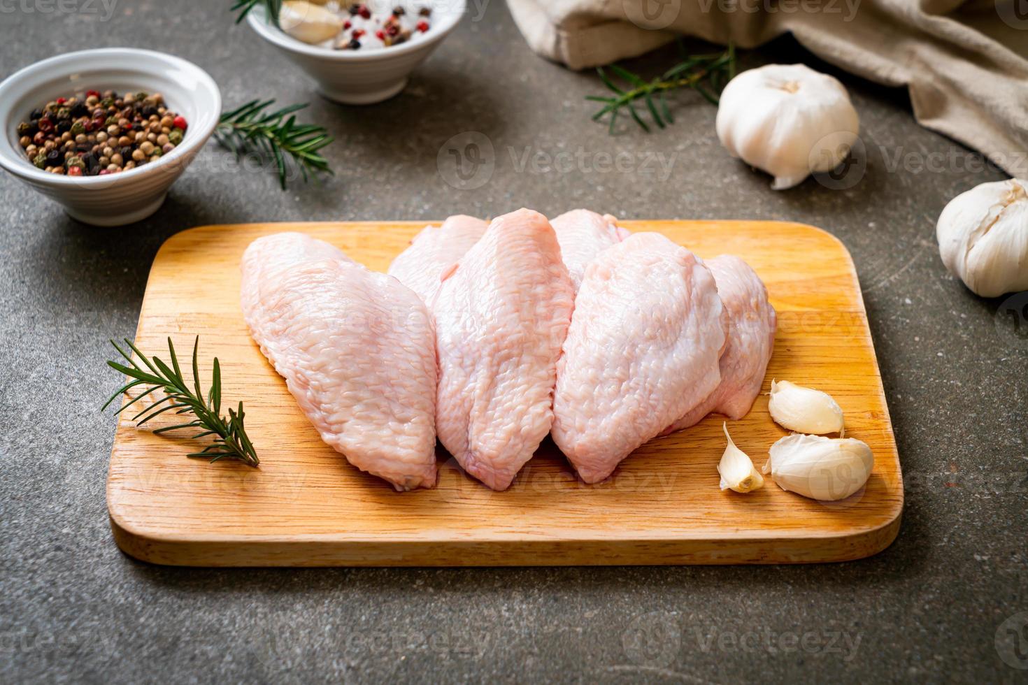 ailes de poulet fraîches et crues sur planche de bois avec des ingrédients photo