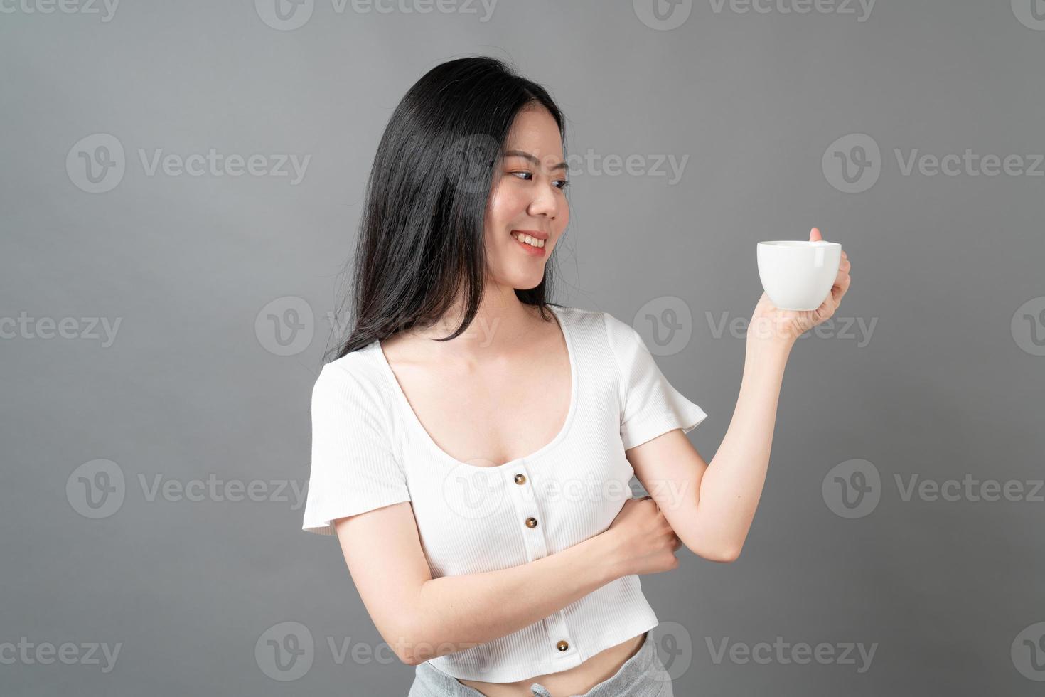 jeune femme asiatique avec un visage heureux et une main tenant une tasse de café photo