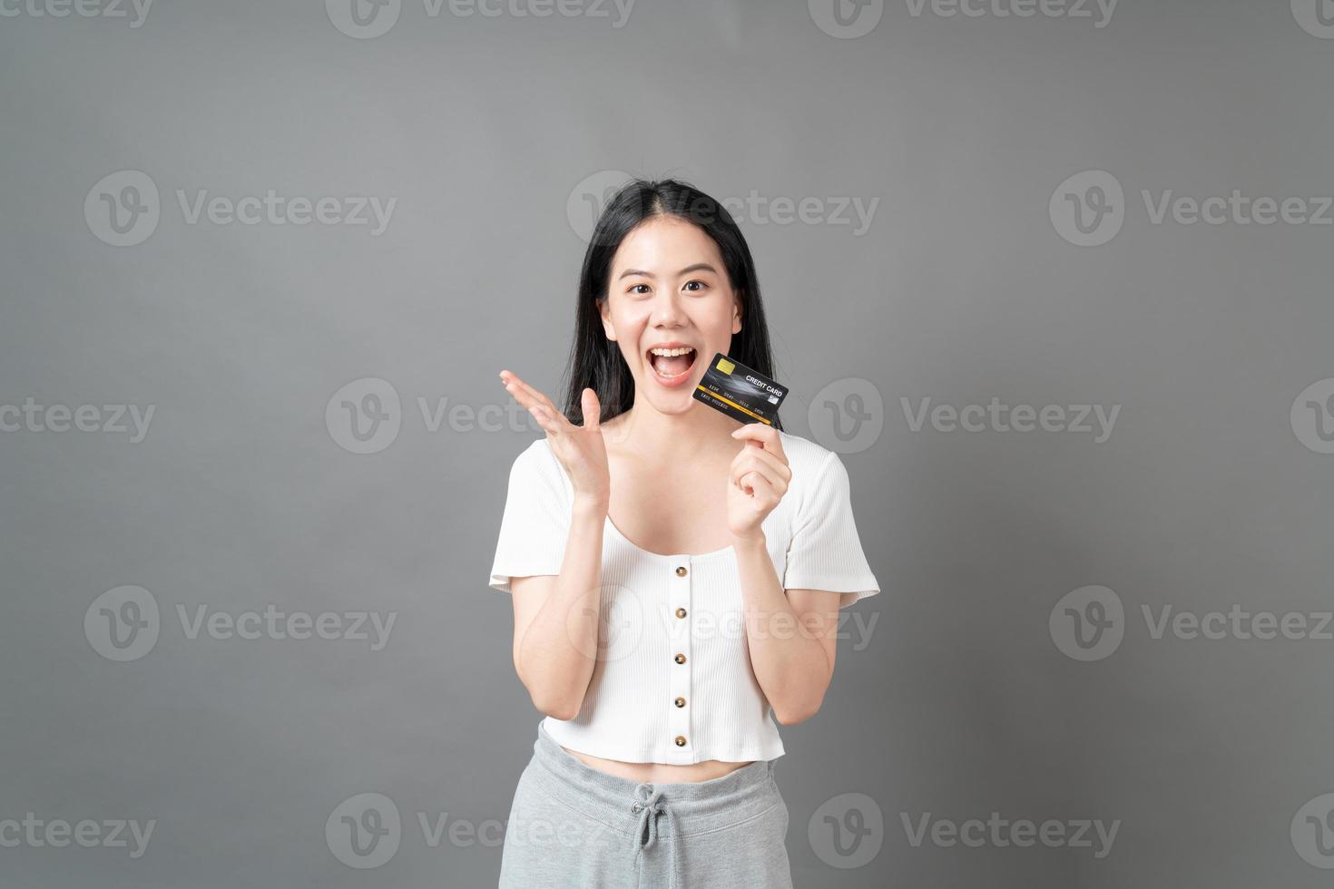 femme asiatique avec un visage heureux et présentant une carte de crédit en main montrant la confiance pour effectuer le paiement photo