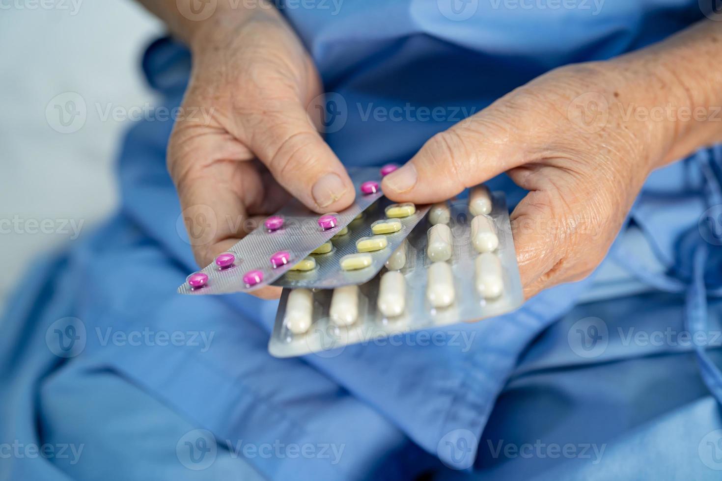 Senior asiatique ou âgée vieille dame femme patient tenant des pilules de capsule d'antibiotiques sous blister pour le traitement de l'infection patient à l'hôpital photo