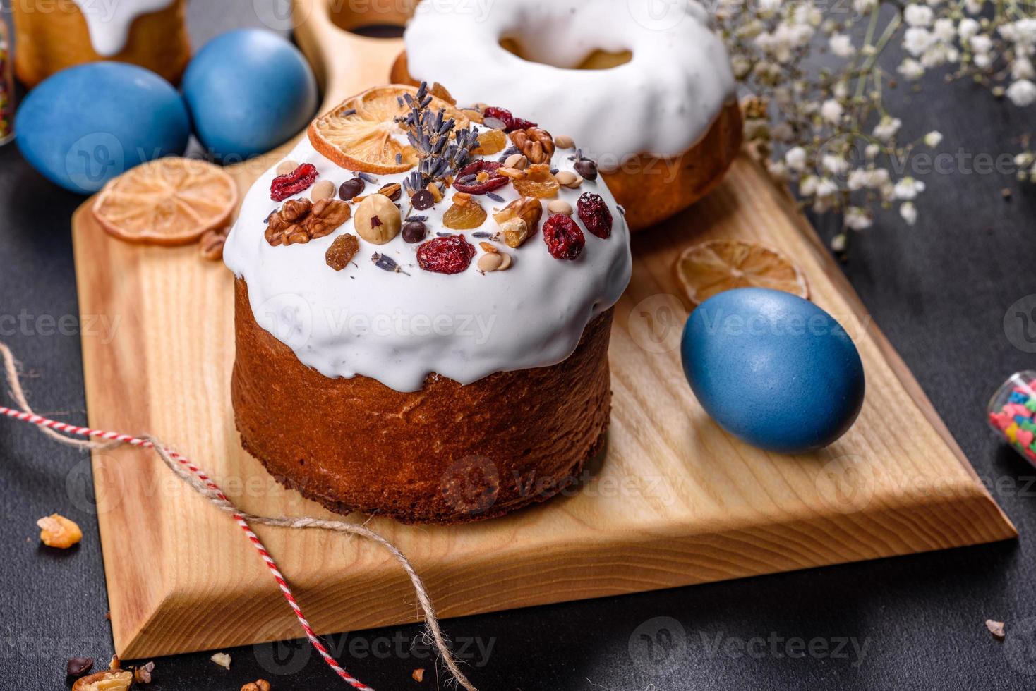 gâteaux de fête avec glaçage blanc, noix et raisins secs avec œufs de pâques sur la table de fête photo