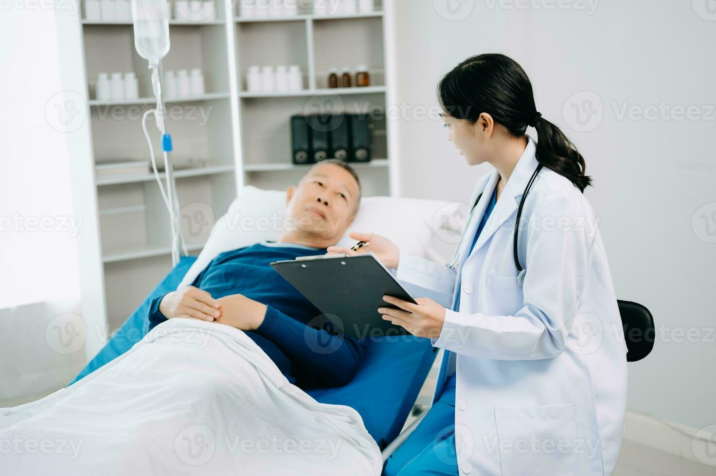 asiatique médecin dans blanc costume prendre Remarques tandis que discuter et asiatique âgé, homme patient qui mensonge sur lit avec recevoir saline Solution dans hôpital photo