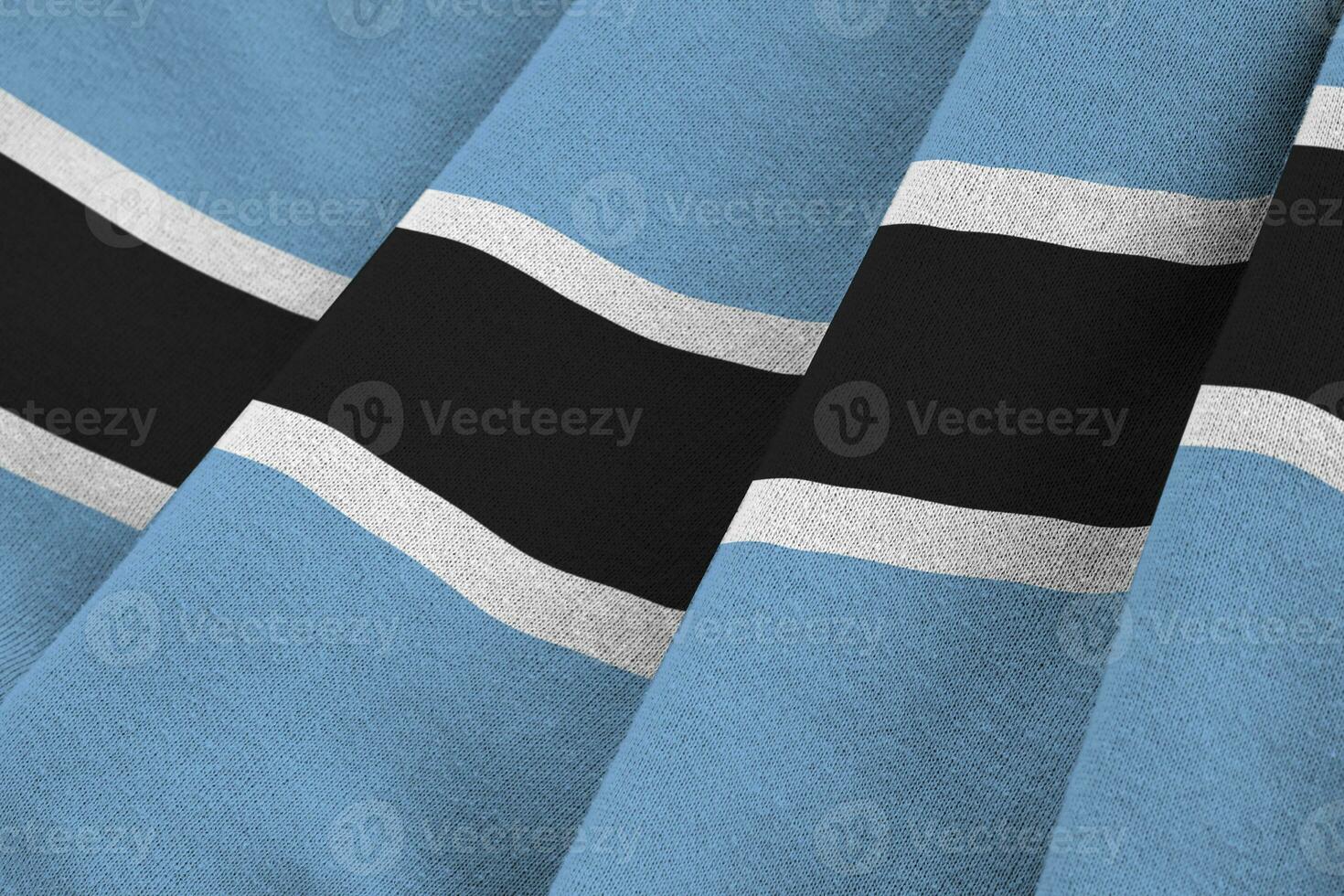 drapeau du botswana avec de grands plis agitant de près sous la lumière du studio à l'intérieur. les symboles et couleurs officiels de la bannière photo