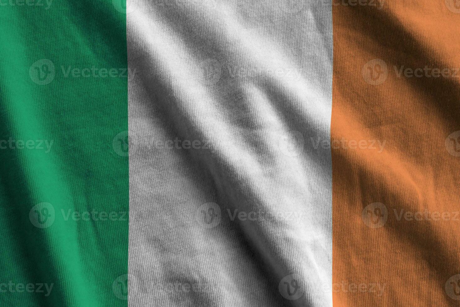drapeau irlandais avec de grands plis agitant de près sous la lumière du studio à l'intérieur. les symboles et couleurs officiels de la bannière photo