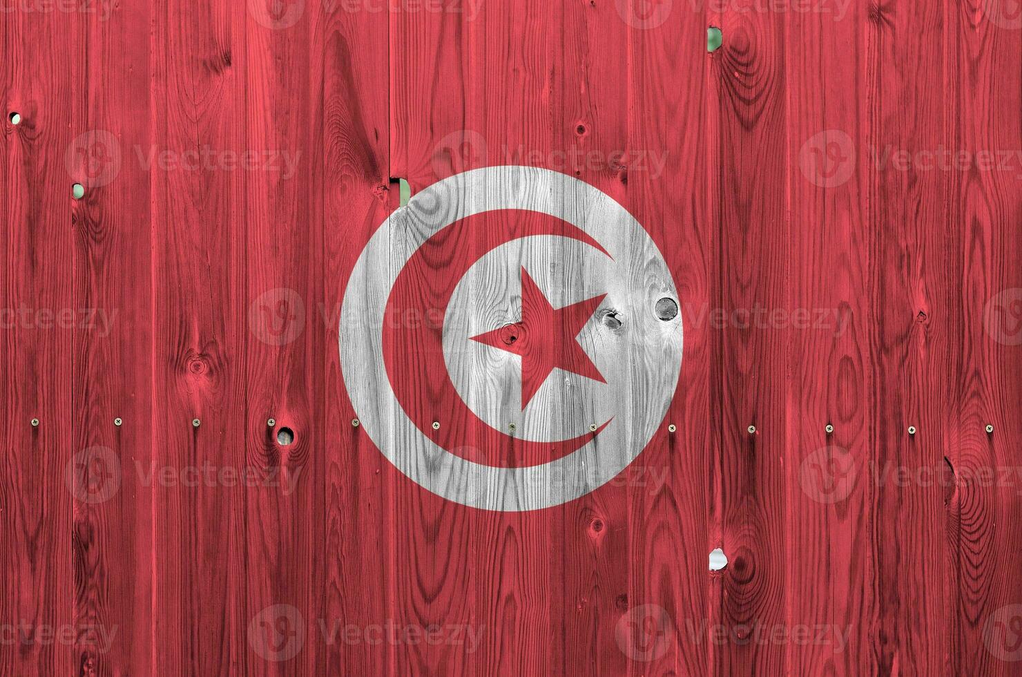 drapeau tunisien représenté dans des couleurs de peinture vives sur un vieux mur en bois. bannière texturée sur fond rugueux photo