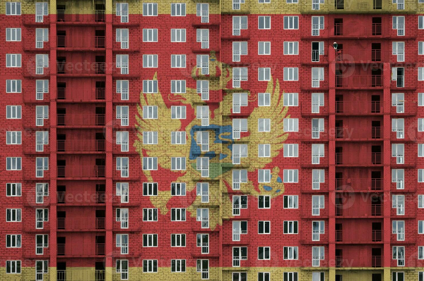 Monténégro drapeau représenté dans peindre couleurs sur à plusieurs étages résidentielle bâtiment en dessous de construction. texturé bannière sur brique mur Contexte photo