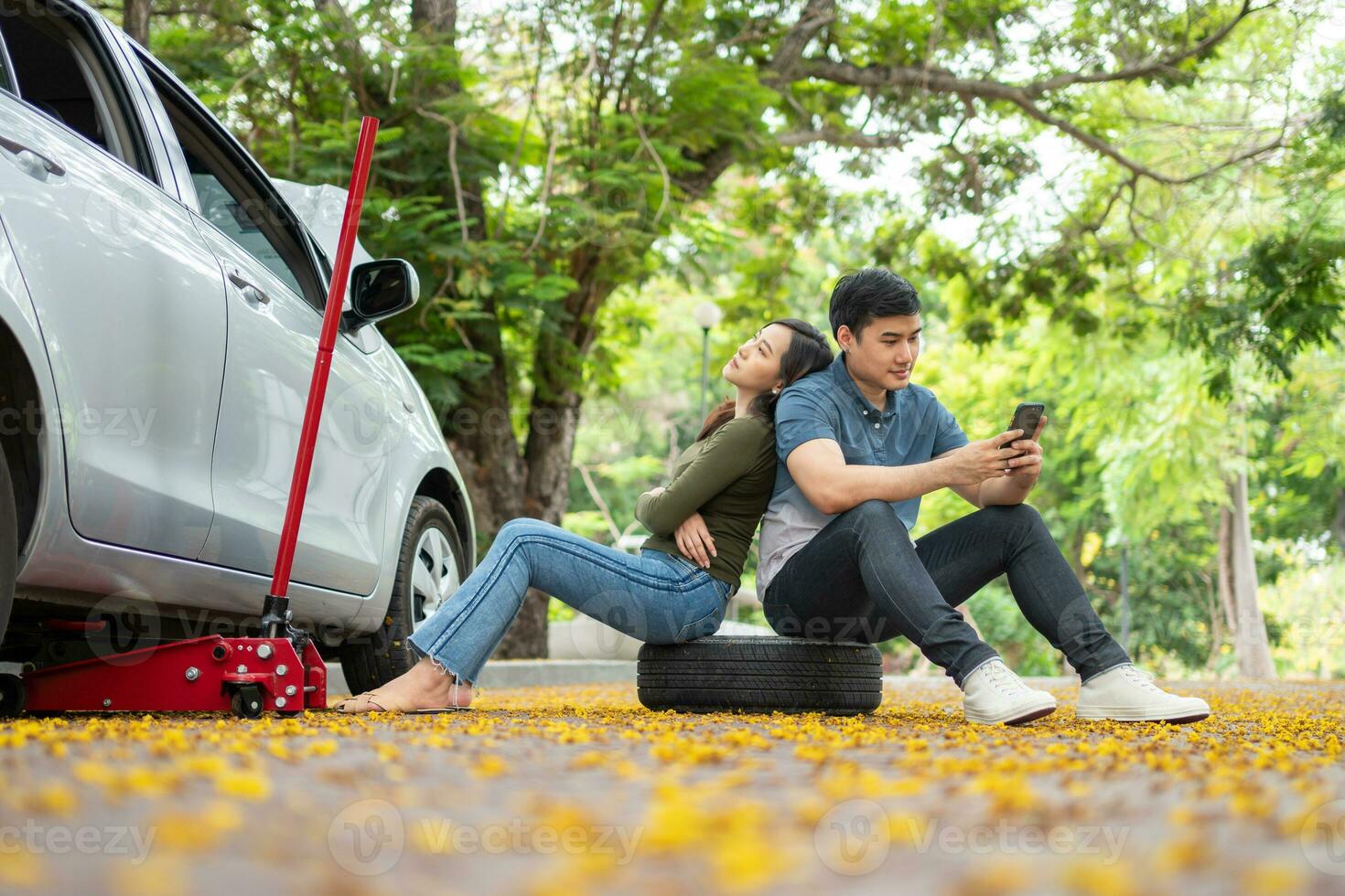 asiatique couple en utilisant téléphone intelligent pour assistance après une voiture panne sur rue. concept de véhicule moteur problème ou accident et urgence Aidez-moi de professionnel mécanicien photo