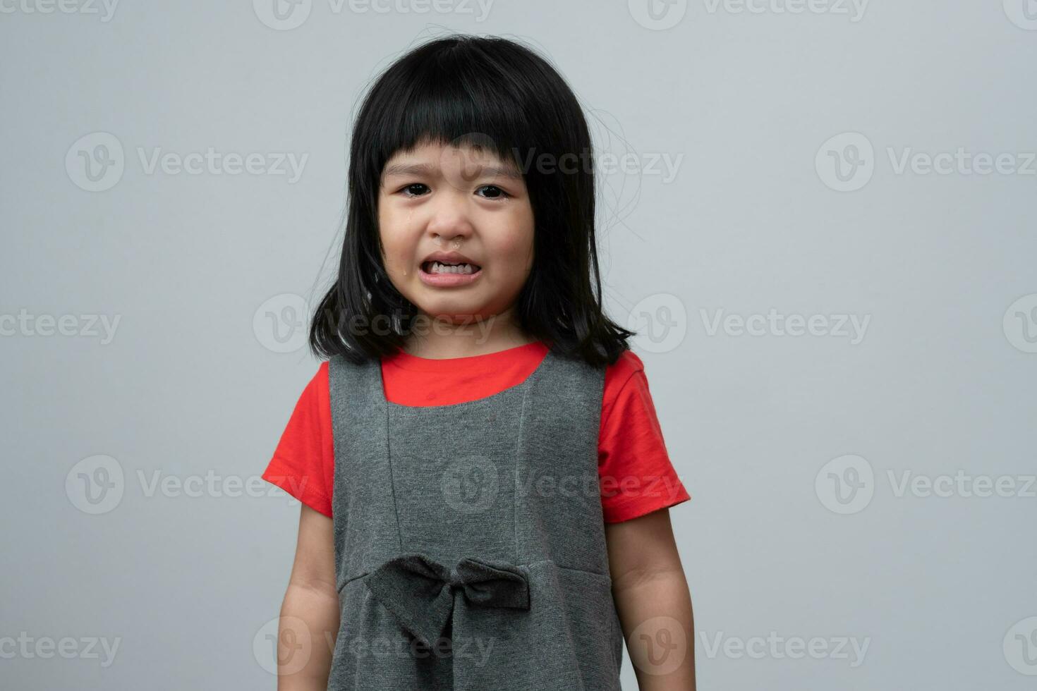 portrait d'une petite fille asiatique en colère, triste et en pleurs sur fond blanc isolé, l'émotion d'un enfant lorsqu'il est en colère et fou, expression d'émotion grincheuse. concept de contrôle émotionnel des enfants photo