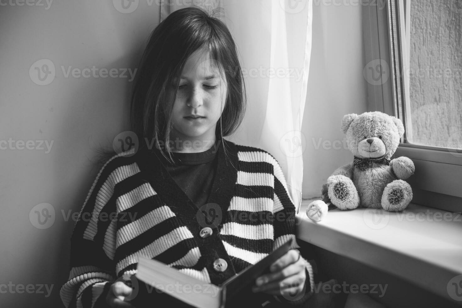 adolescent fille en train de lire une livre à Accueil par le fenêtre photo