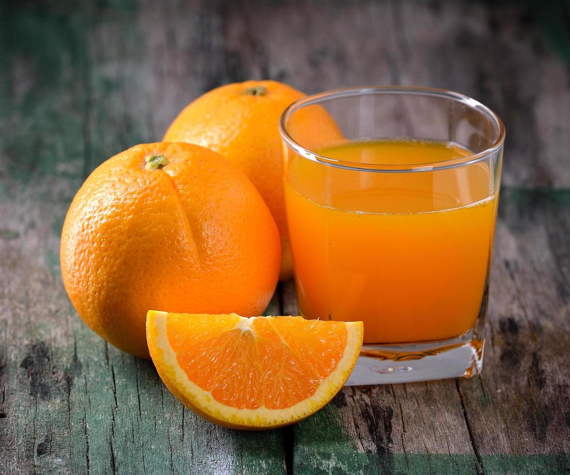 verre de jus d'orange et oranges fraîches sur bois photo