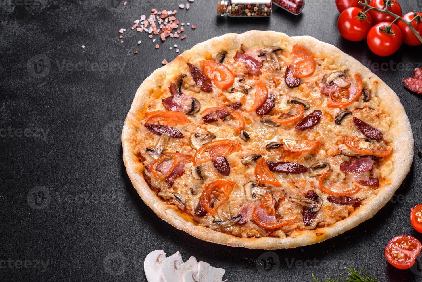 délicieuse pizza fraîche faite dans un four à sole avec des tomates, des saucisses et des champignons photo