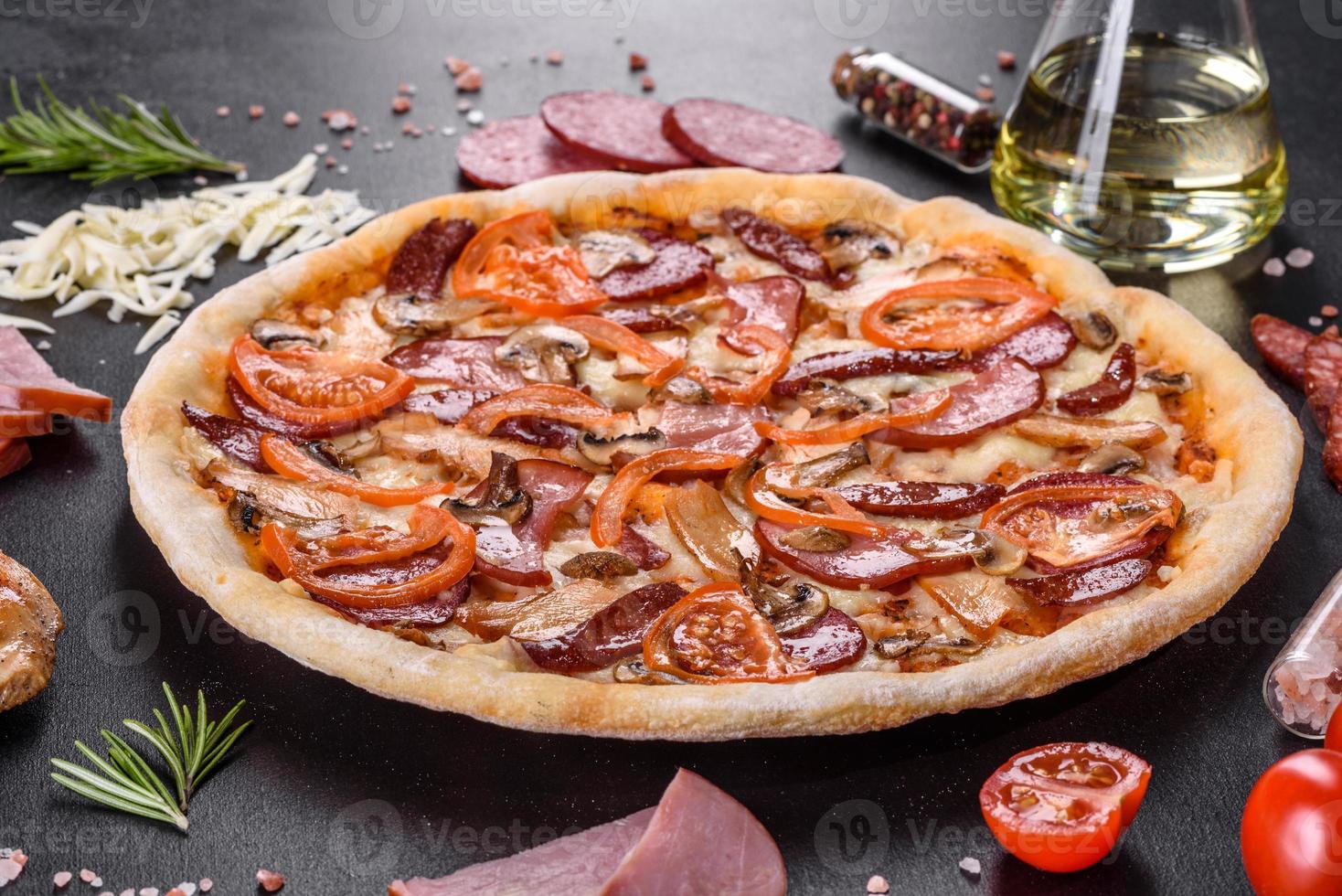 délicieuse pizza fraîche faite dans un four à sole avec des saucisses, du poivre et des tomates photo