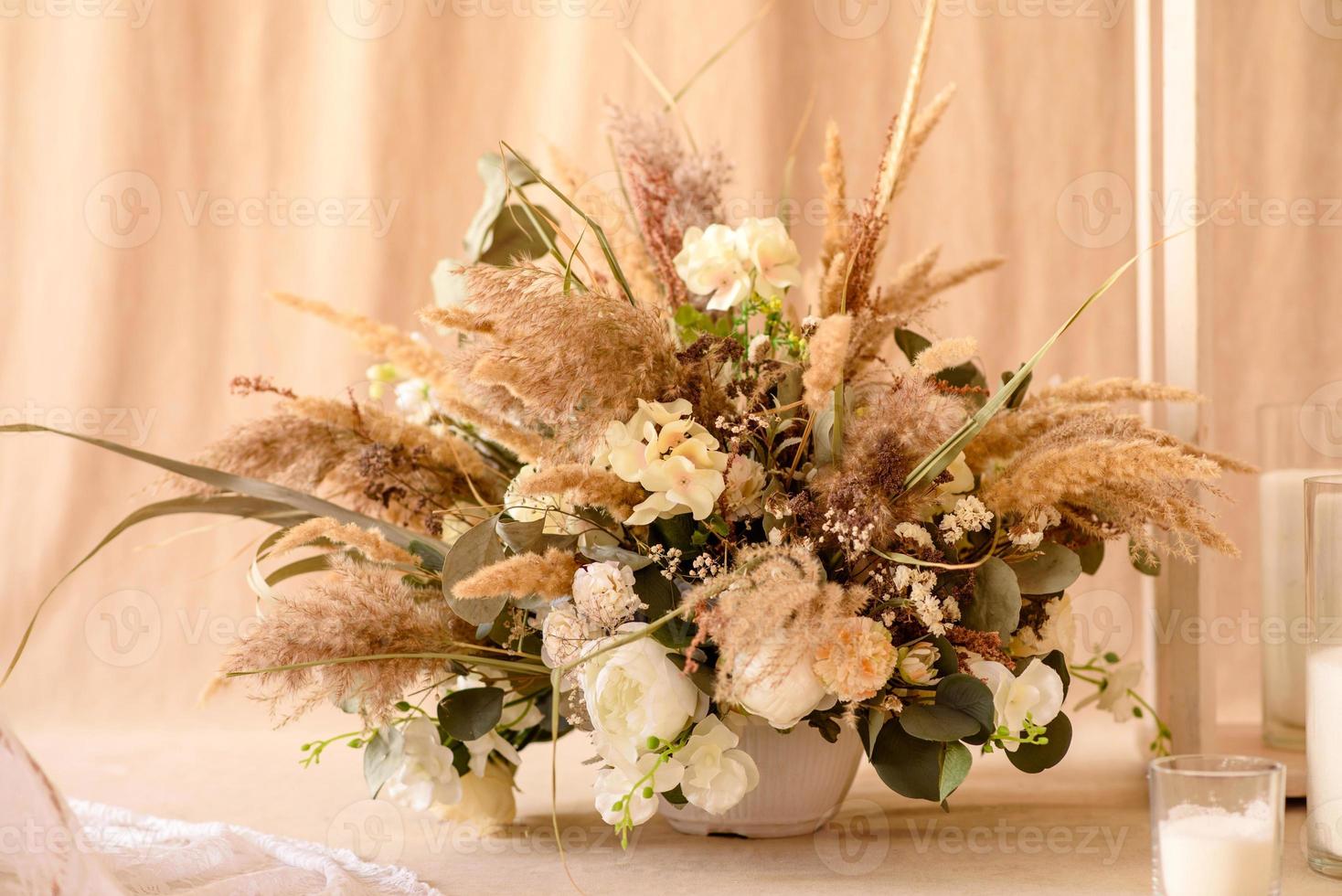 décorations de belles fleurs sèches dans un vase blanc sur fond de tissu beige photo