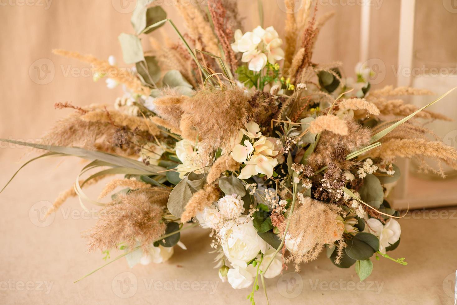 décorations de belles fleurs sèches dans un vase blanc sur fond de tissu beige photo