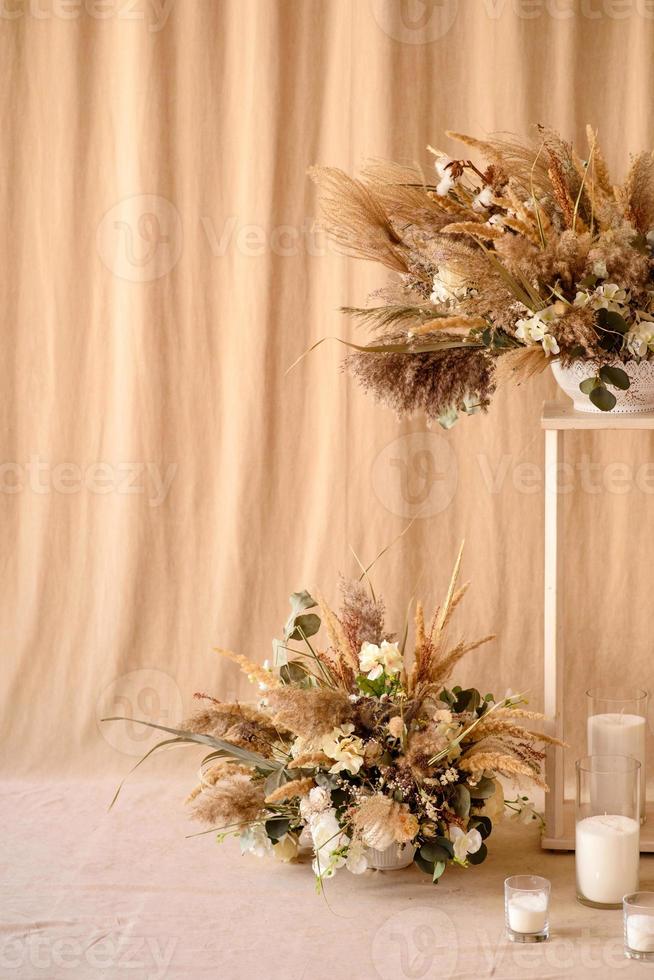 décorations de belles fleurs sèches dans un vase blanc sur fond de tissu beige photo