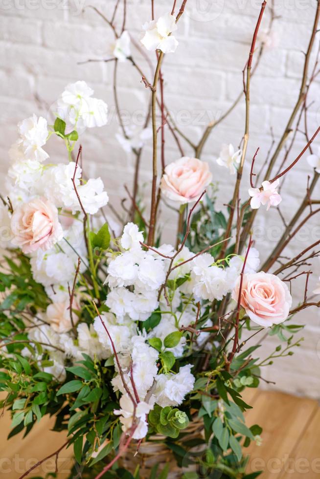 décorations de branches avec de belles fleurs roses et blanches dans le panier sur fond de mur de briques blanches photo