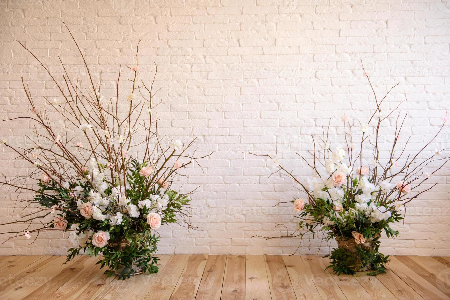 décorations de branches avec de belles fleurs roses et blanches dans le panier sur fond de mur de briques blanches photo