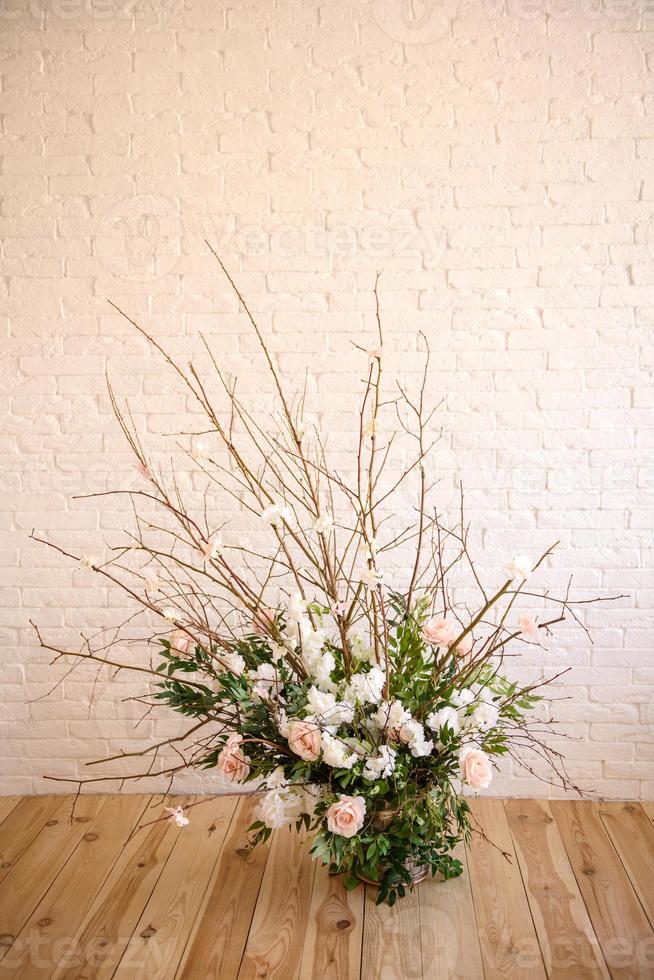 décorations de branches avec de belles fleurs roses et blanches dans le panier sur fond de mur de briques blanches photo