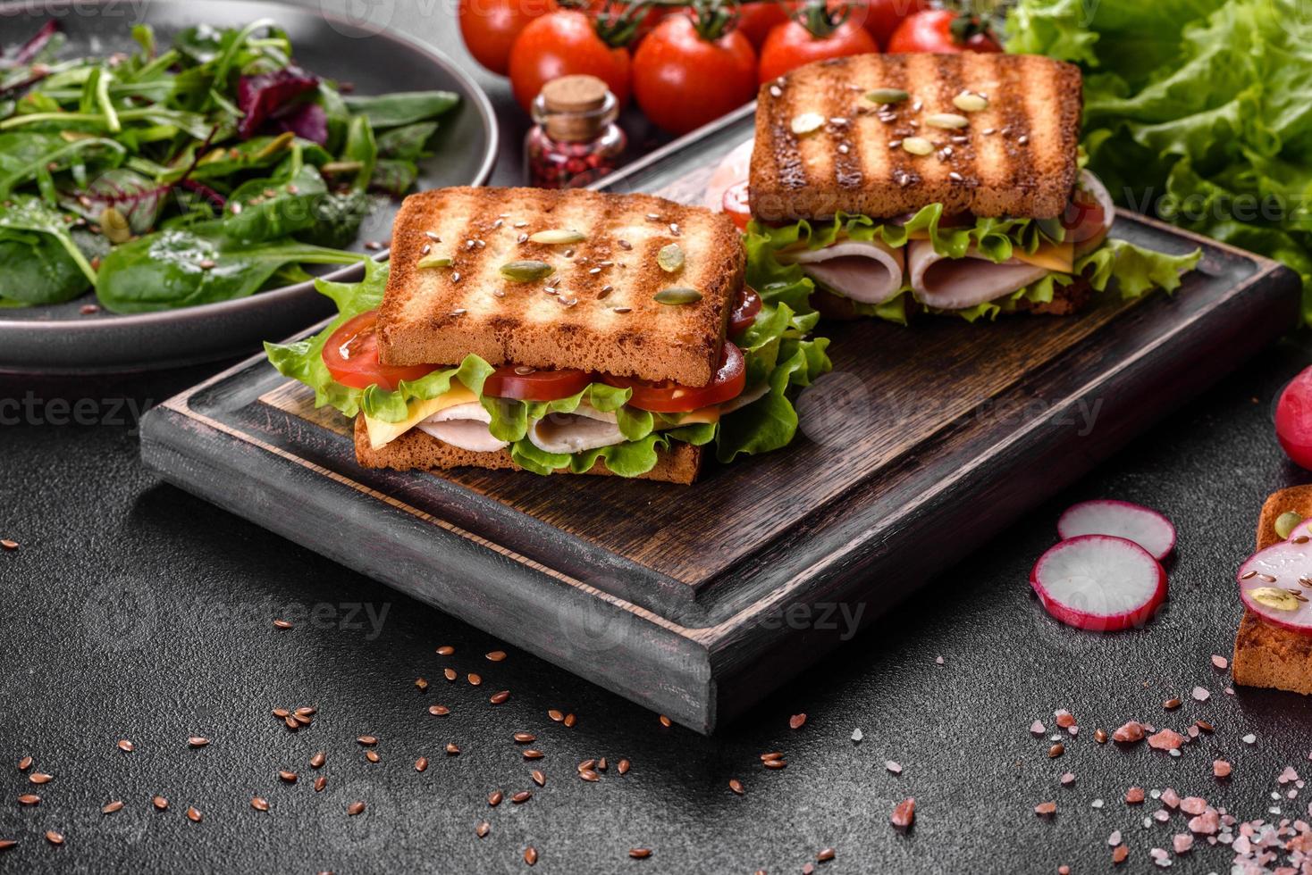 délicieux sandwich avec des toasts croustillants, du jambon, de la laitue et des tomates photo