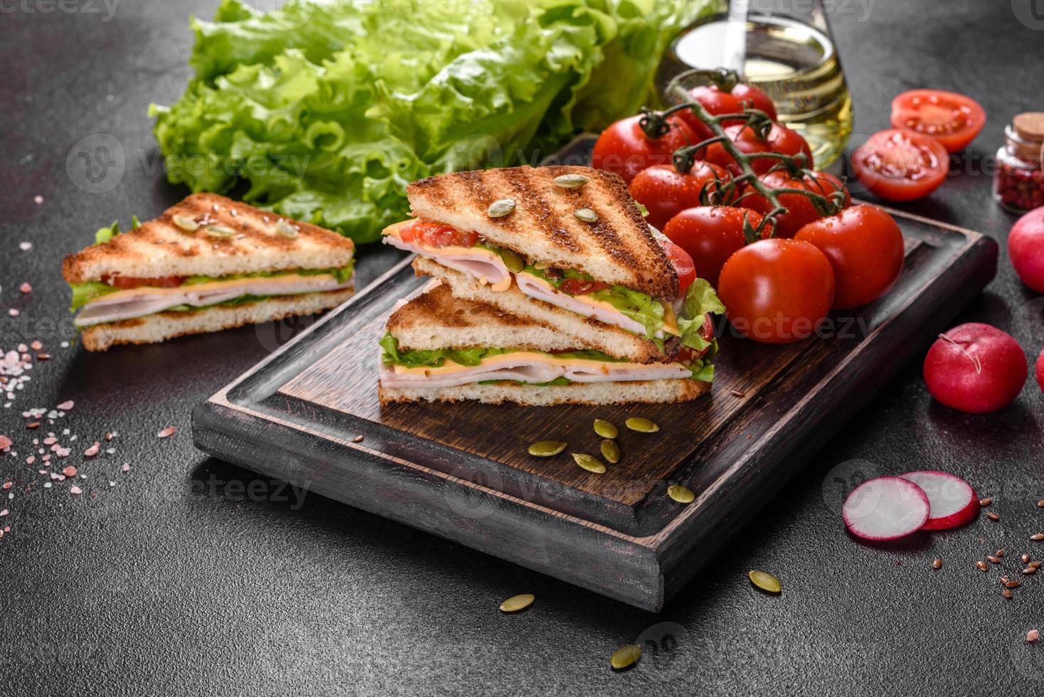 délicieux sandwich avec des toasts croustillants, du jambon, de la laitue et des tomates photo