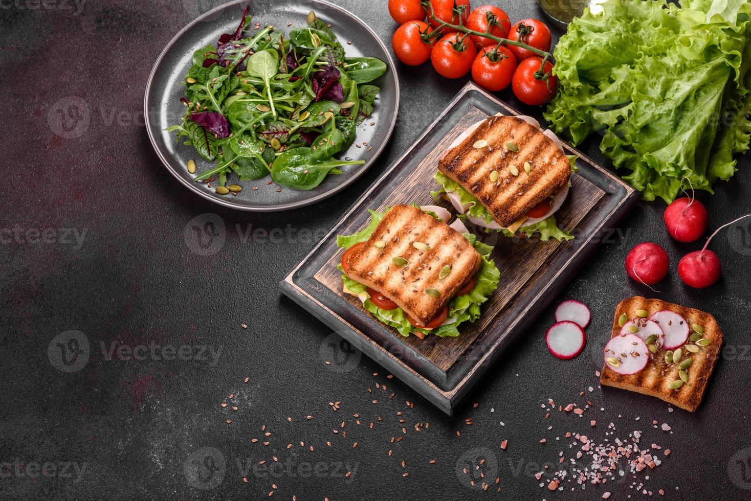 délicieux sandwich avec des toasts croustillants, du jambon, de la laitue et des tomates photo