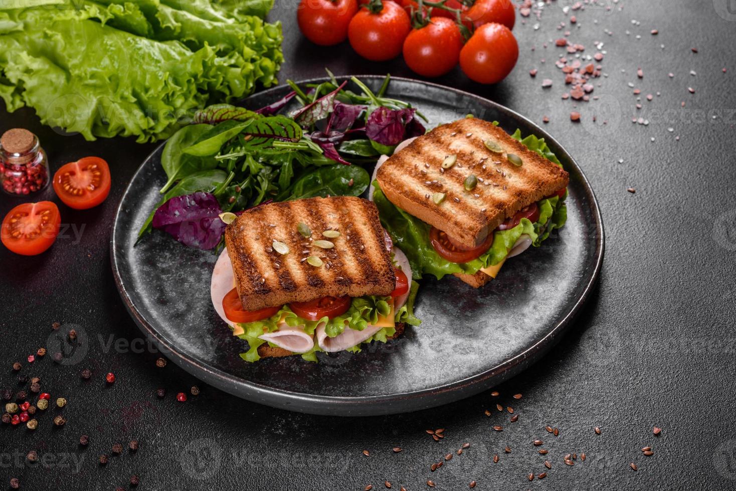 délicieux sandwich avec des toasts croustillants, du jambon, de la laitue et des tomates photo