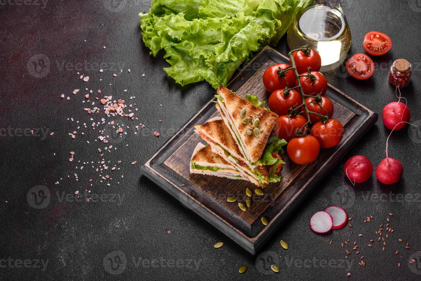 délicieux sandwich avec des toasts croustillants, du jambon, de la laitue et des tomates photo