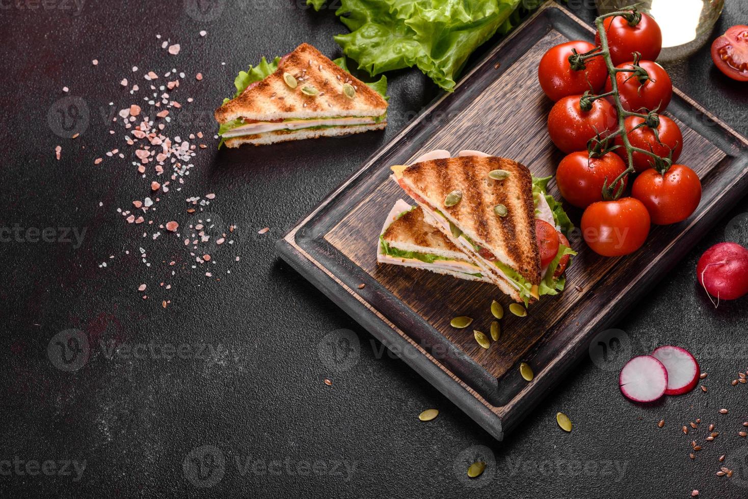 délicieux sandwich avec des toasts croustillants, du jambon, de la laitue et des tomates photo