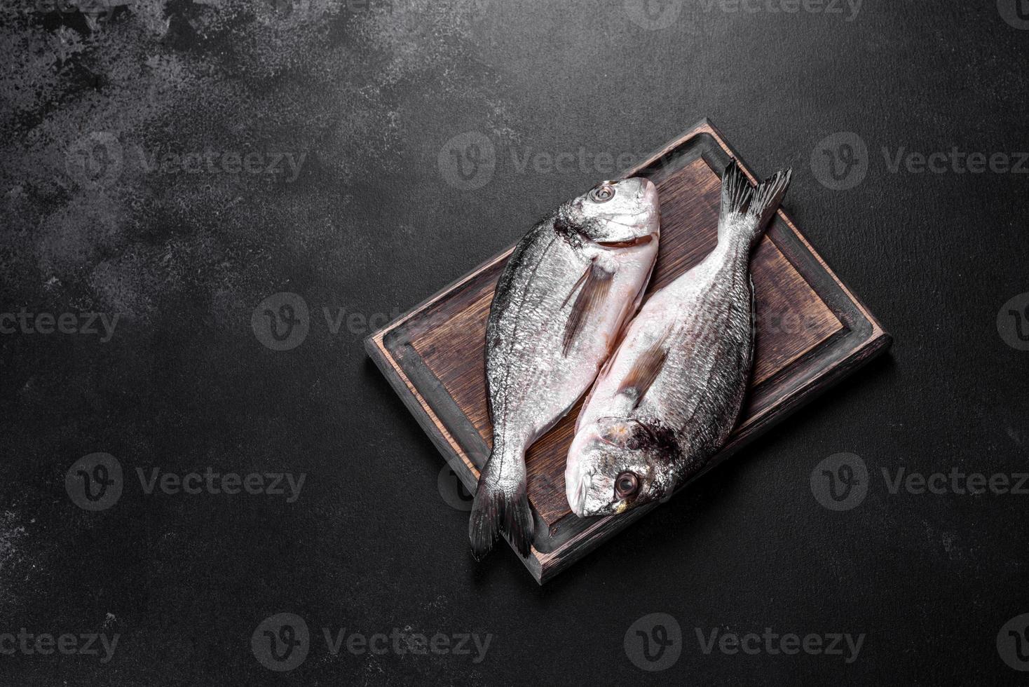 poisson dorado cru aux épices cuisant sur une planche à découper. daurade de poisson frais photo