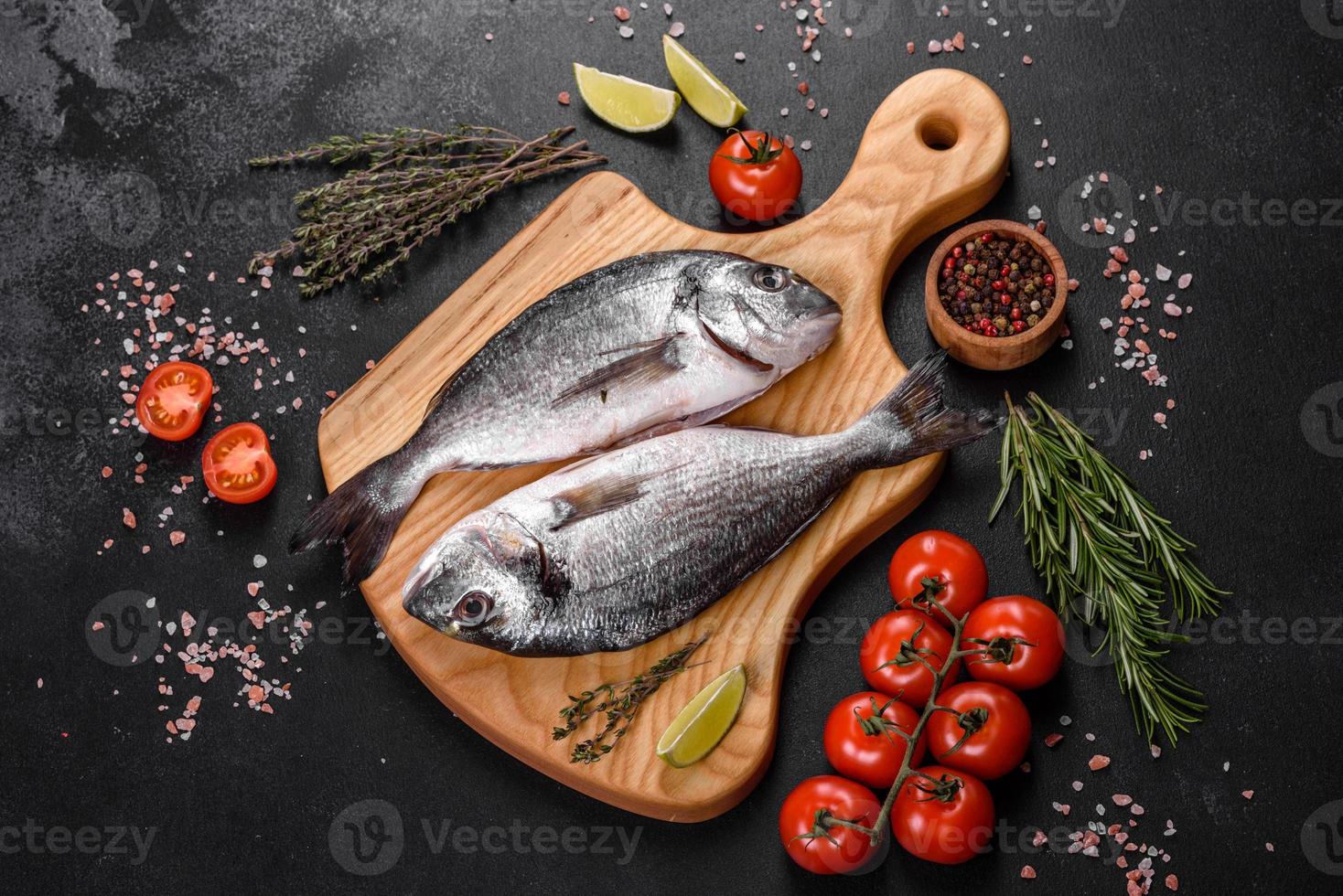 poisson dorado cru aux épices cuisant sur une planche à découper. daurade de poisson frais photo