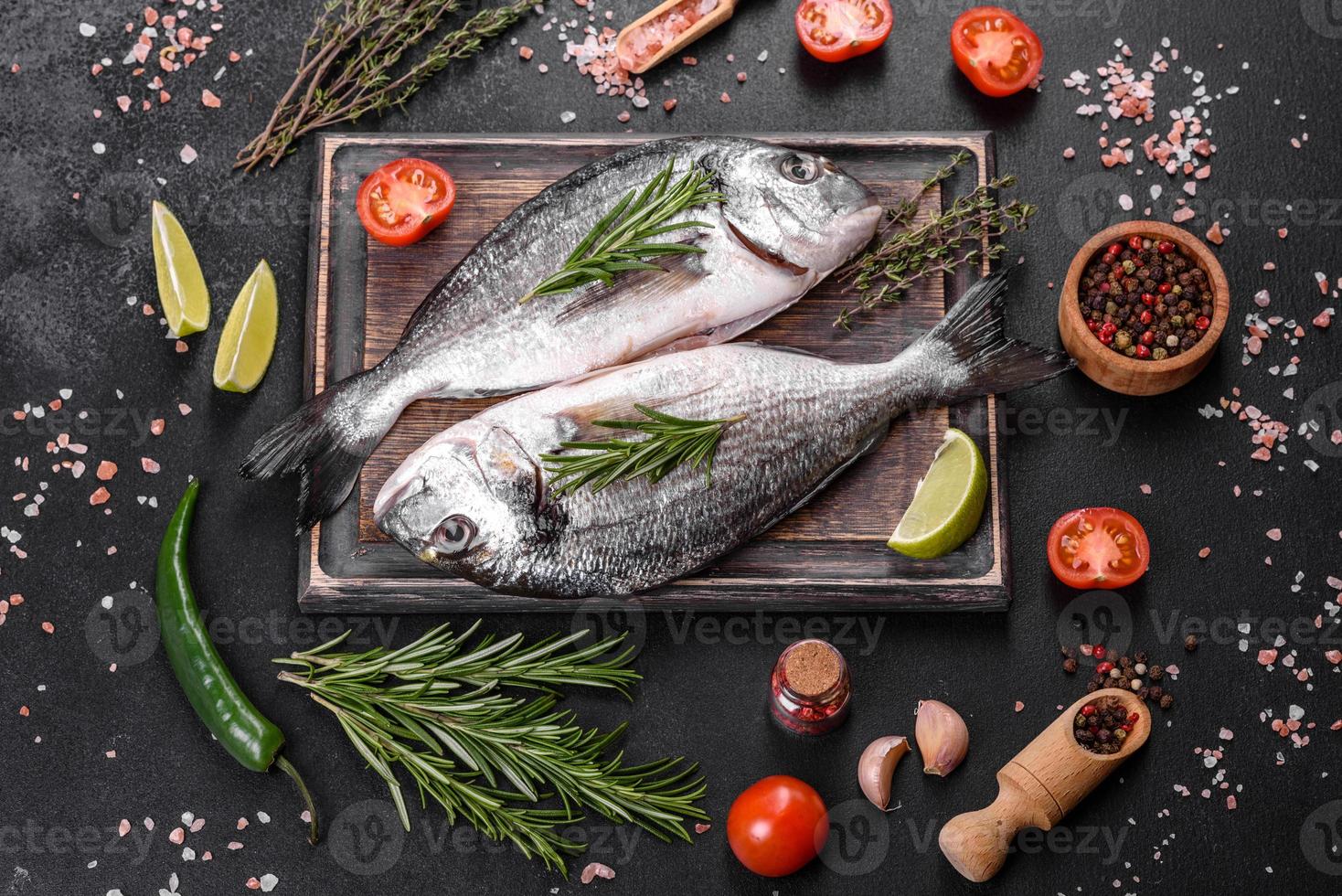 poisson dorado cru aux épices cuisant sur une planche à découper. daurade de poisson frais photo