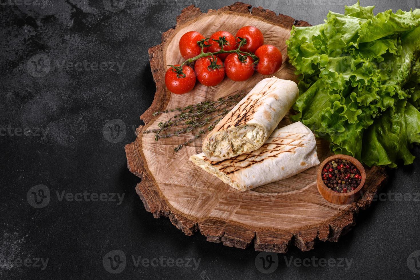 délicieux shawarma frais avec de la viande et des légumes sur une table en béton foncé photo