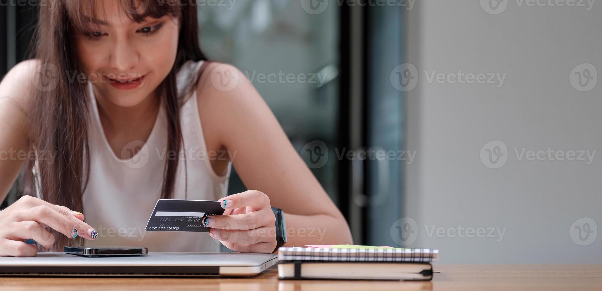 femme souriante utilise un téléphone portable pour faire des achats en ligne avec une carte de crédit photo